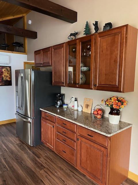kitchen featuring light stone countertops, lofted ceiling with beams, freestanding refrigerator, dark wood-type flooring, and glass insert cabinets