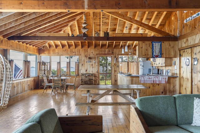 living room featuring hardwood / wood-style flooring, high vaulted ceiling, and wood walls