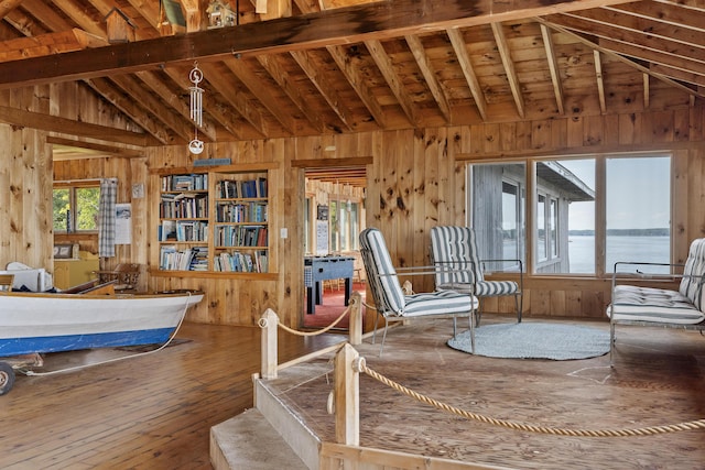 dining area featuring wood-type flooring, lofted ceiling with beams, wood walls, and a water view