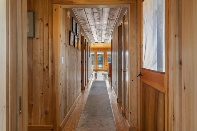 hallway featuring light colored carpet and wooden walls