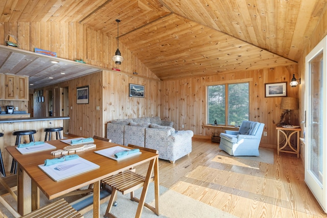 dining room with vaulted ceiling, light wood-type flooring, wooden walls, and wood ceiling