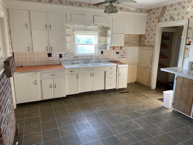 kitchen featuring ceiling fan, sink, white cabinetry, and decorative backsplash