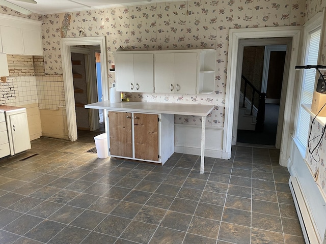 kitchen with baseboard heating, white cabinets, and ornamental molding