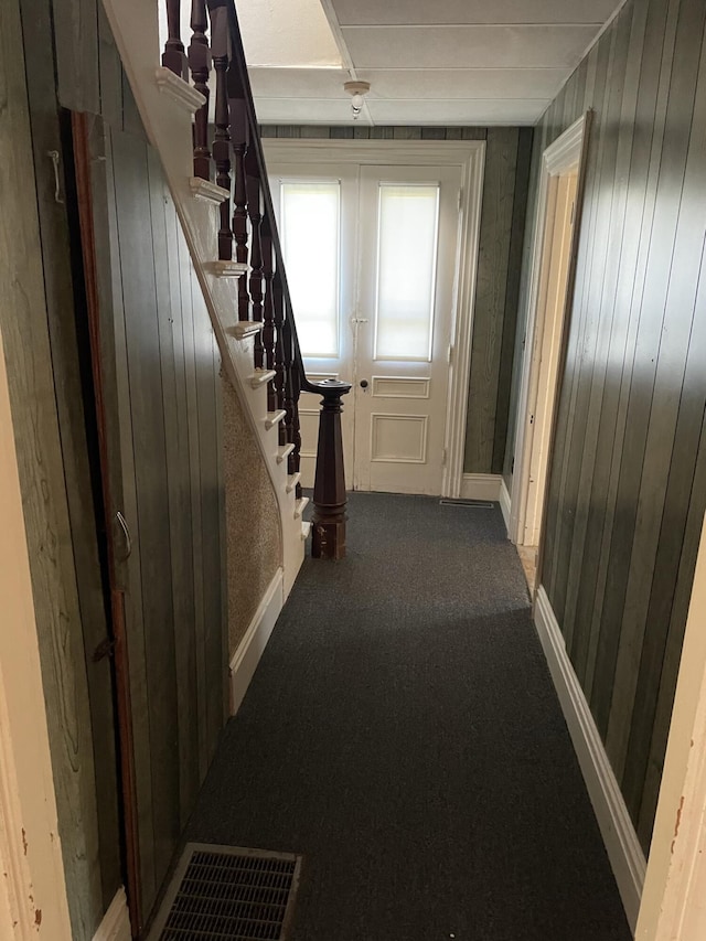 hall featuring carpet flooring and wooden walls