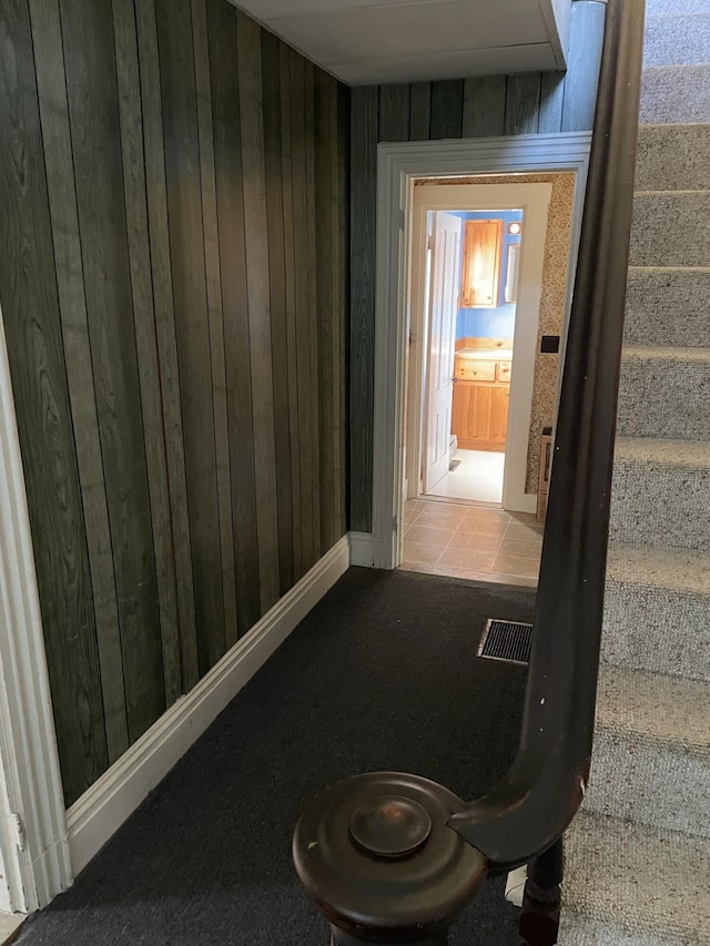 corridor featuring light carpet and wooden walls