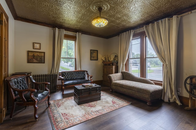 living area featuring radiator heating unit, crown molding, and hardwood / wood-style flooring