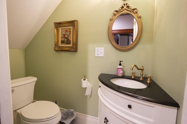 bathroom featuring toilet, vanity, and vaulted ceiling