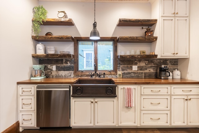 kitchen featuring decorative light fixtures, butcher block counters, tasteful backsplash, sink, and stainless steel dishwasher