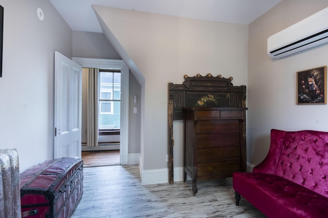 sitting room with a wall mounted AC, light hardwood / wood-style floors, and a baseboard radiator