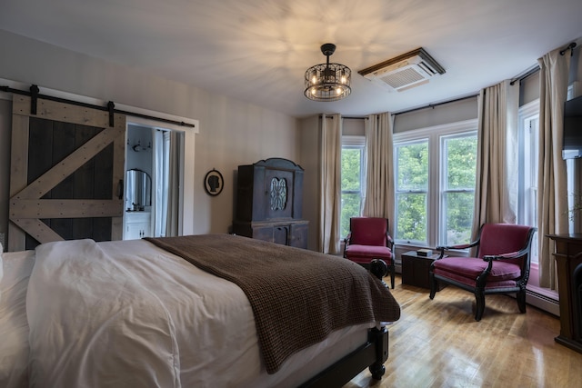 bedroom with a barn door, light hardwood / wood-style flooring, and a notable chandelier