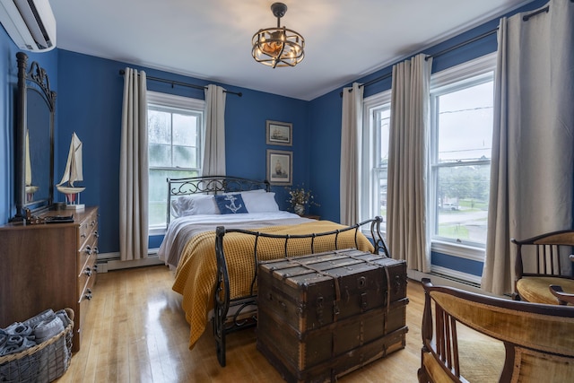 bedroom featuring baseboard heating, a wall mounted air conditioner, multiple windows, and light hardwood / wood-style flooring