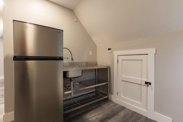 kitchen with lofted ceiling, stainless steel fridge, and dark wood-type flooring