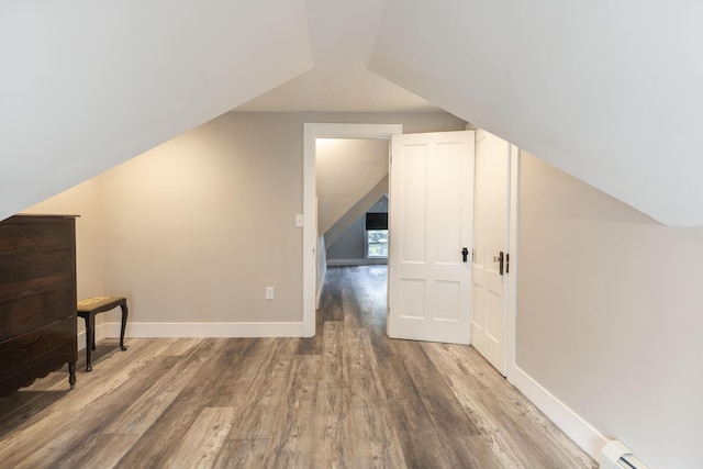 additional living space with a baseboard heating unit, lofted ceiling, and hardwood / wood-style floors