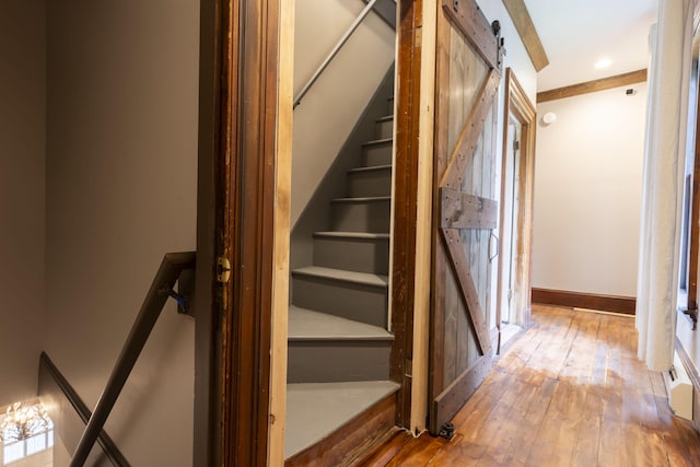 staircase featuring a barn door and wood-type flooring