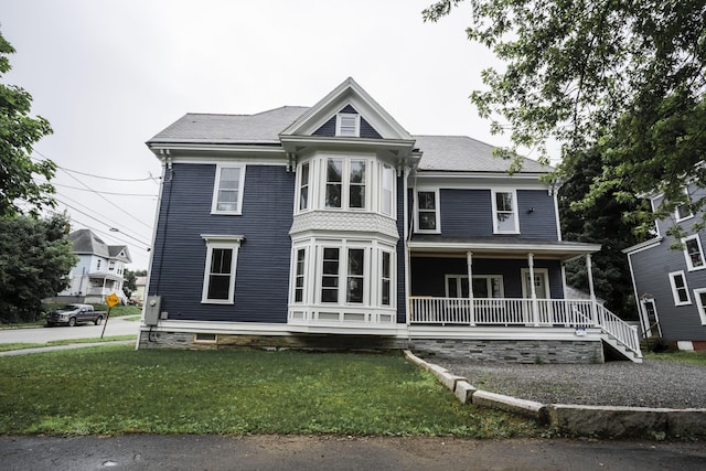 victorian house with a front lawn and a porch