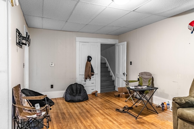 sitting room with a paneled ceiling and wood-type flooring