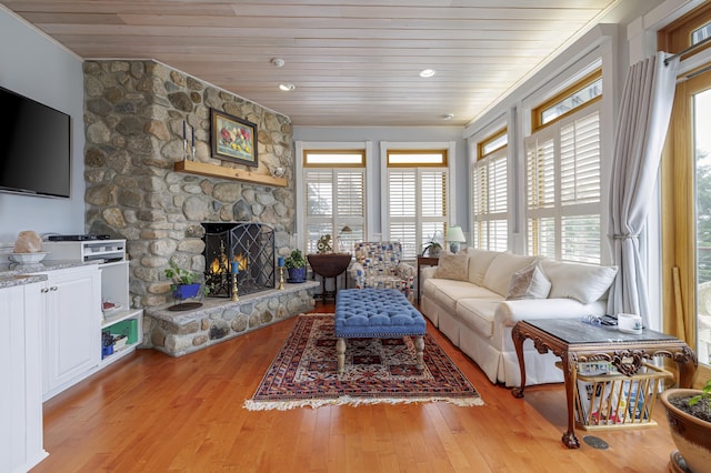 living room featuring light wood-type flooring, wooden ceiling, and a fireplace