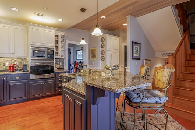 kitchen with appliances with stainless steel finishes, backsplash, a center island with sink, and sink