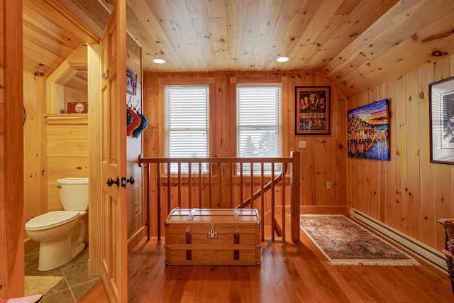 interior space with lofted ceiling, hardwood / wood-style floors, wooden walls, wooden ceiling, and a baseboard radiator