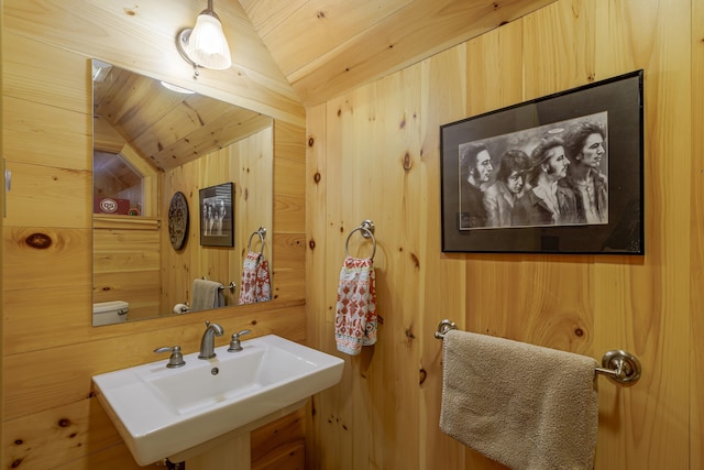 bathroom featuring vaulted ceiling, wood ceiling, wood walls, and sink