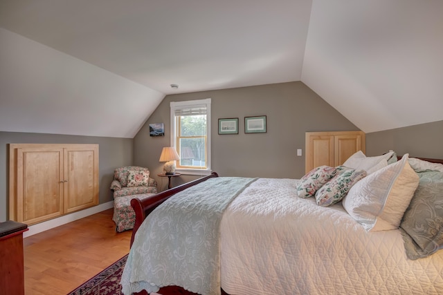 bedroom with vaulted ceiling and hardwood / wood-style flooring