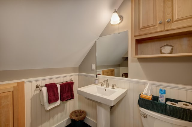 bathroom featuring toilet, wooden walls, and vaulted ceiling