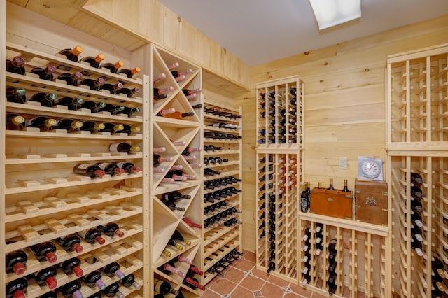 wine area featuring tile patterned flooring and wooden walls