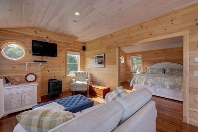 bedroom featuring lofted ceiling, dark hardwood / wood-style floors, wood walls, and a wood stove