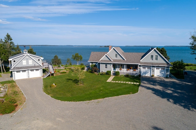 view of front facade featuring covered porch, a front lawn, a garage, and a water view