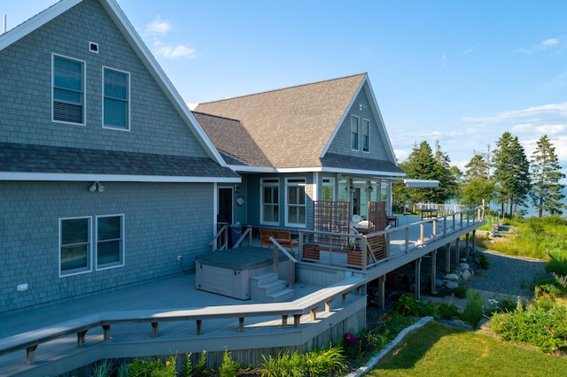 rear view of house featuring a wooden deck and a hot tub