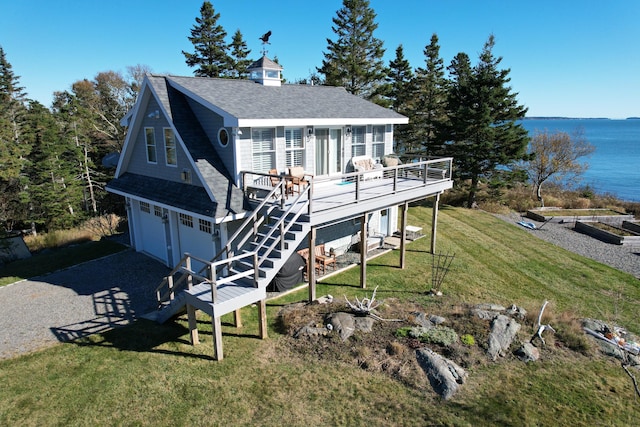 back of house featuring a garage, a deck with water view, and a lawn