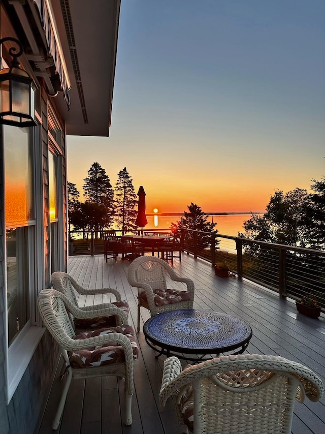 deck at dusk featuring a water view