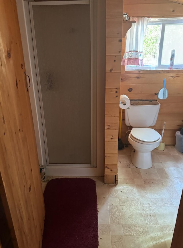 bathroom featuring toilet, walk in shower, and wood walls