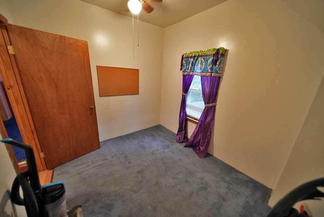 spare room featuring ceiling fan and dark carpet