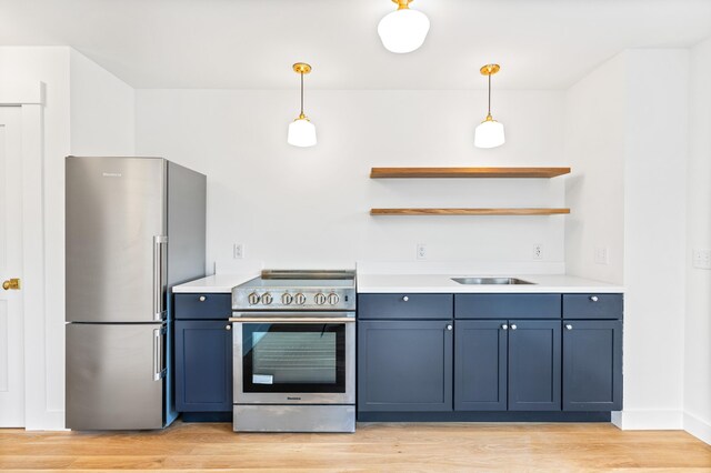 kitchen featuring appliances with stainless steel finishes, pendant lighting, light hardwood / wood-style flooring, and blue cabinetry