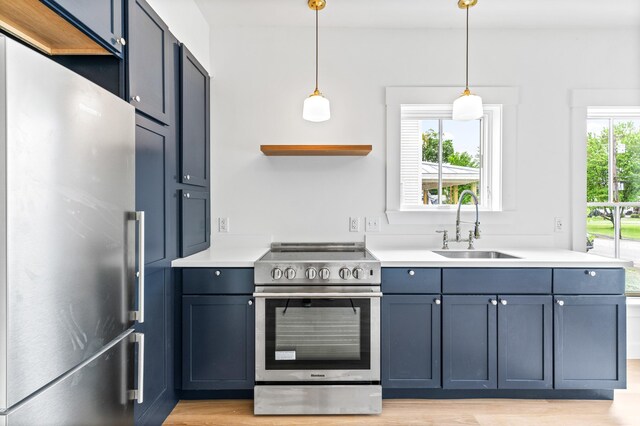 kitchen with appliances with stainless steel finishes, light hardwood / wood-style flooring, sink, hanging light fixtures, and blue cabinetry