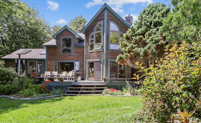 back of property featuring a deck and a lawn