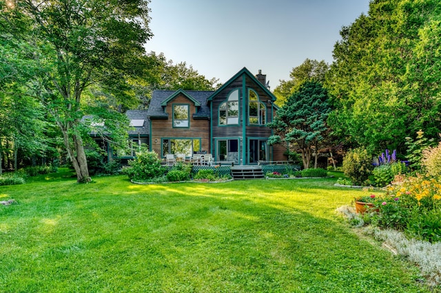 back of house with a deck and a lawn