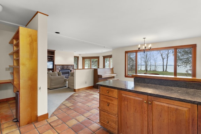 kitchen featuring light tile patterned floors, pendant lighting, a fireplace, and a notable chandelier