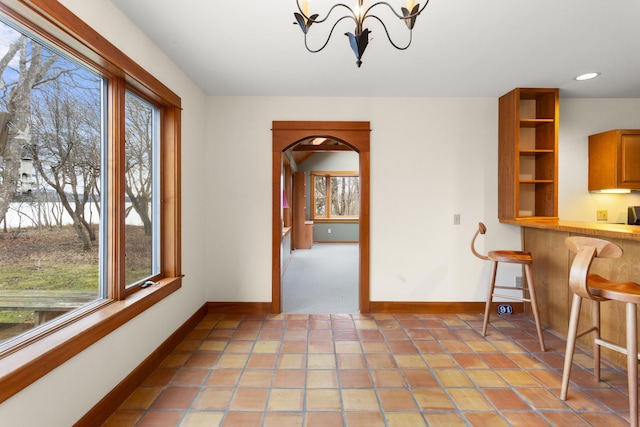 unfurnished dining area featuring a wealth of natural light, light carpet, and an inviting chandelier