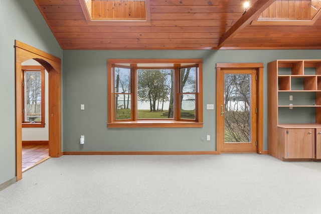 unfurnished living room with vaulted ceiling with skylight, wood ceiling, and carpet