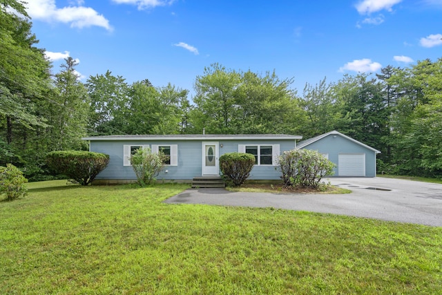 view of front of property featuring a garage, a front lawn, and an outbuilding