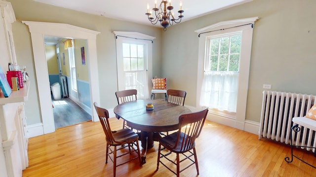 dining space with radiator heating unit, a chandelier, and light wood-type flooring