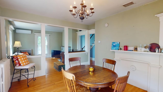 dining space featuring light hardwood / wood-style floors, radiator heating unit, a chandelier, and a wall mounted air conditioner