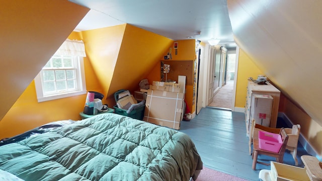 bedroom with vaulted ceiling, hardwood / wood-style flooring, and multiple windows