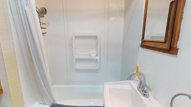 bathroom with shower / bathtub combination with curtain and sink