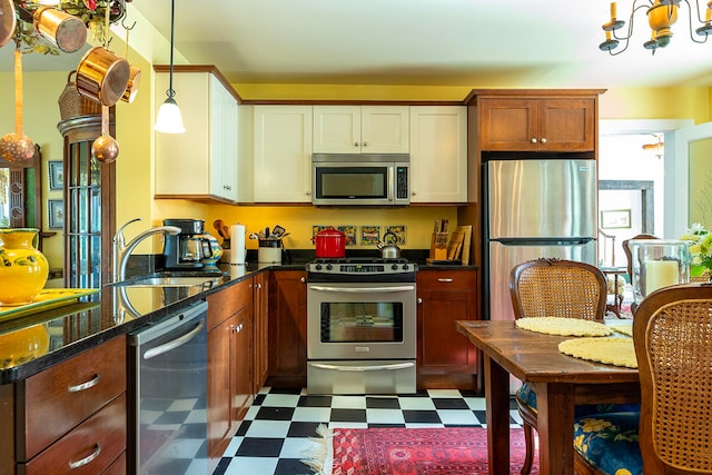 kitchen featuring appliances with stainless steel finishes, sink, dark stone counters, and light tile patterned flooring