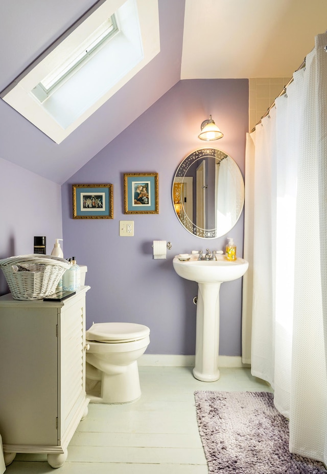 bathroom featuring hardwood / wood-style floors, lofted ceiling with skylight, and toilet