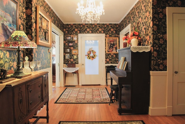 entrance foyer with crown molding, a chandelier, and light wood-type flooring