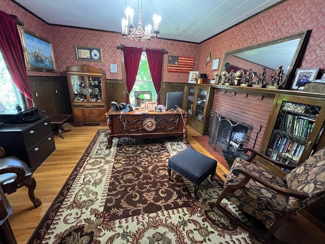 interior space featuring a notable chandelier, a fireplace, light hardwood / wood-style floors, and ornamental molding